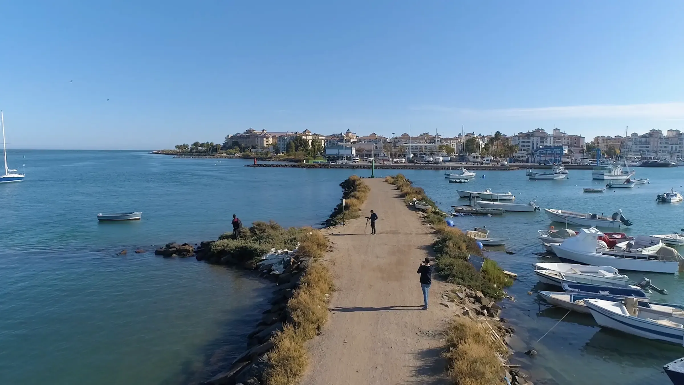 Vista aérea de un pueblo marinero con su puerto y barcas, al final de un camino sobre el agua